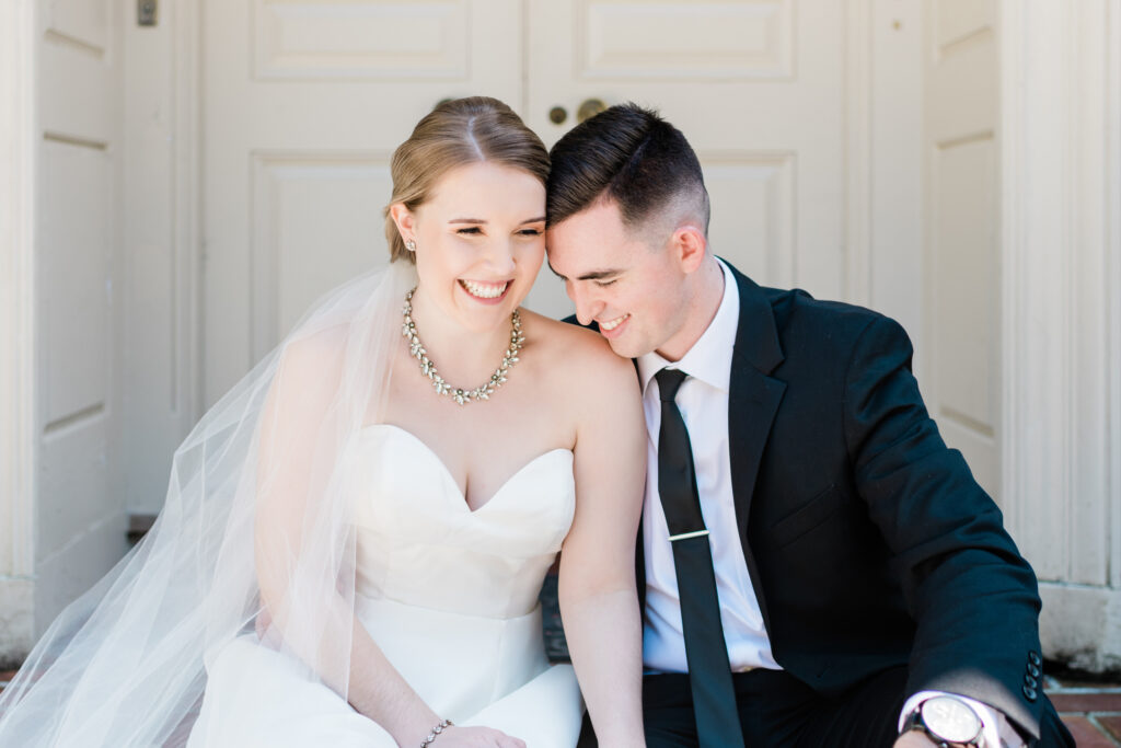 happy bride and groom sitting on stairs. groom in formal black suit. Weddings with Joy. 