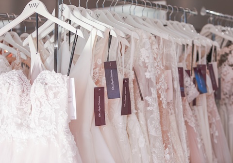 Designer wedding dresses on clothing rack. Weddings With Joy.