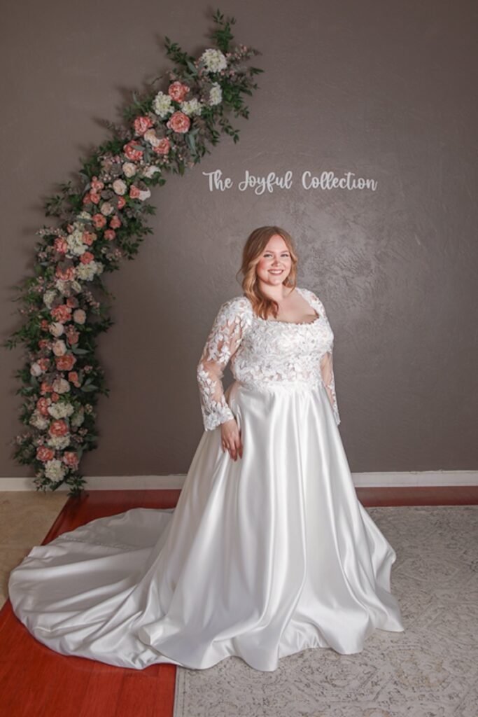 Plus size ball gown wedding dress with lace bodice, illusion lace long sleeves, satin skirt and train. Weddings with Joy.