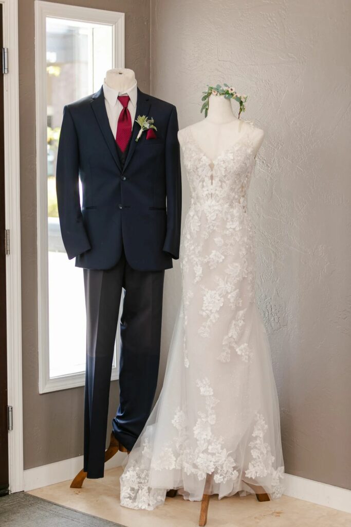 Navy wedding suit with burgundy tie next to fitted lace wedding dress. Weddings with Joy. 