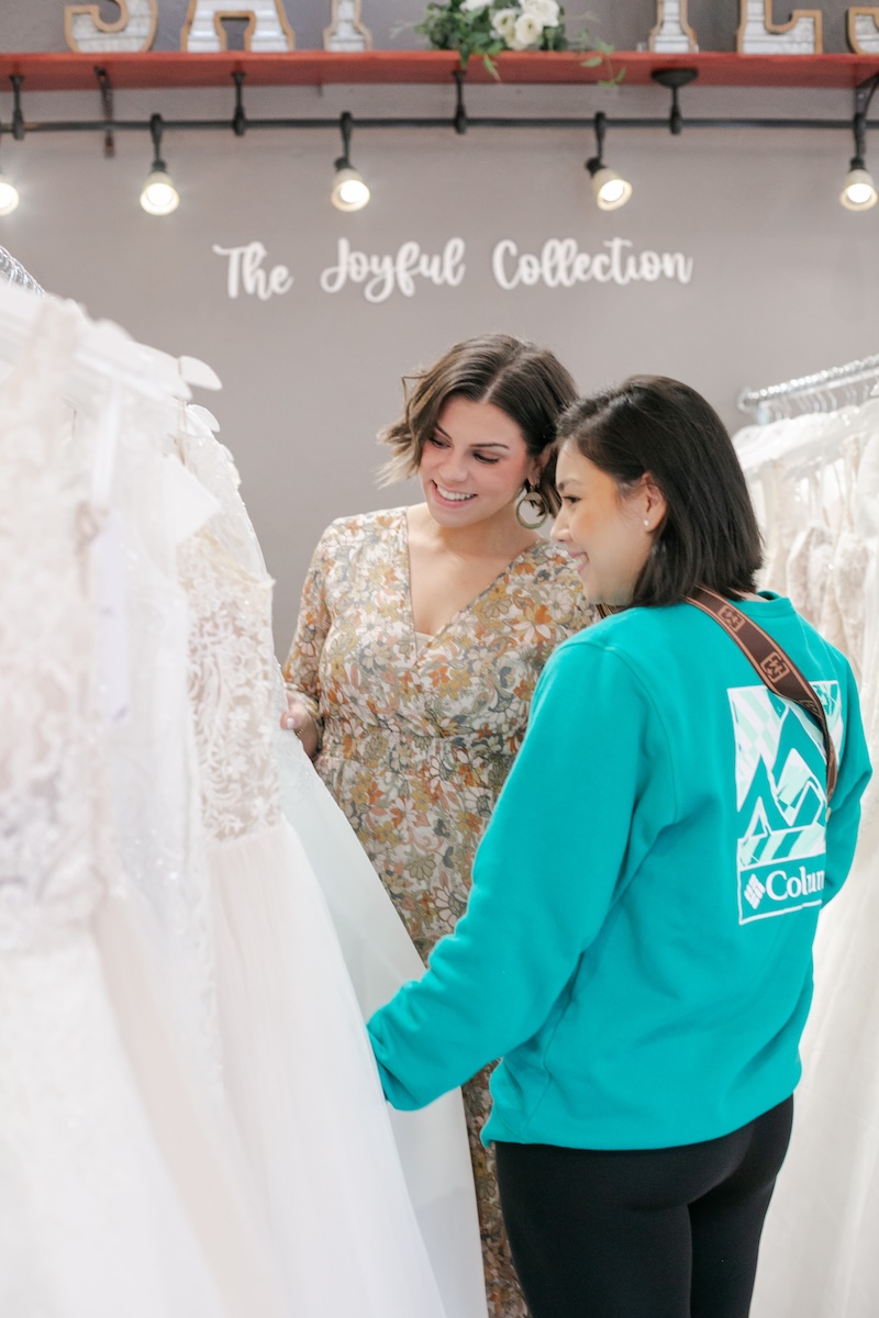 Bride browsing wedding dresses with bridal consultant in bridal store. Weddings with Joy. 