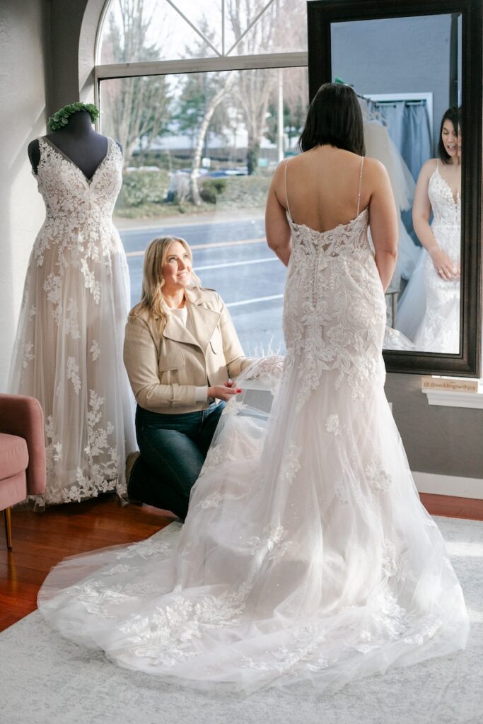 bride tries on fitted lace wedding dress with spaghetti straps. Weddings with Joy. 