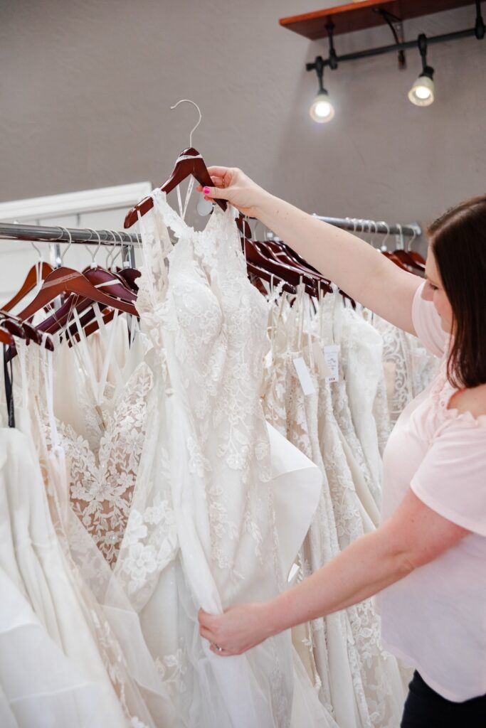 woman shops for a lace, halter neckline wedding dress. weddings with joy. 