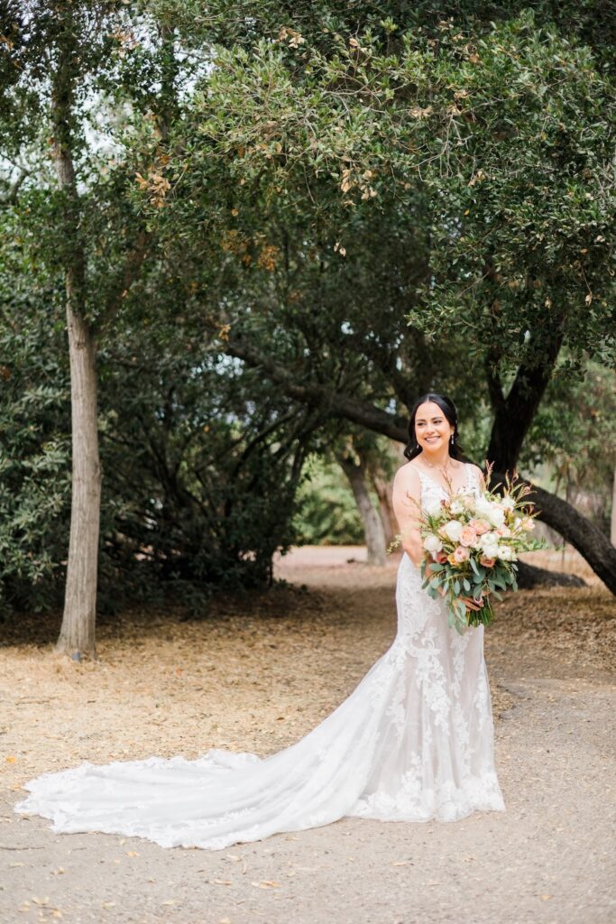 traditional bridal portrait, lace wedding dress with straps and long train. lush bridal bouquet with blush and white blooms. Weddings with Joy.