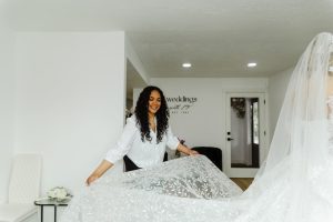 bridal stylist holds out train of bridal dress