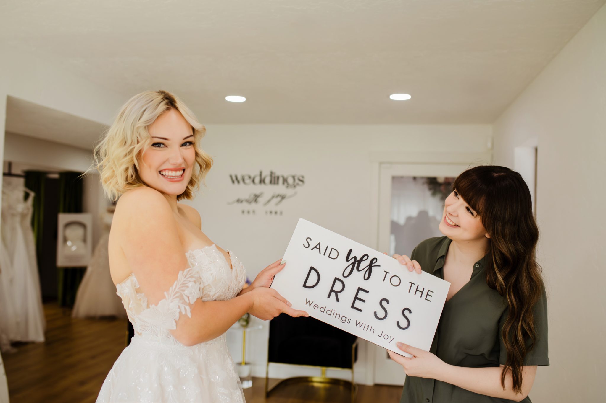 Happy bride and bridal stylist holding sign saying "Said yes to the dress"